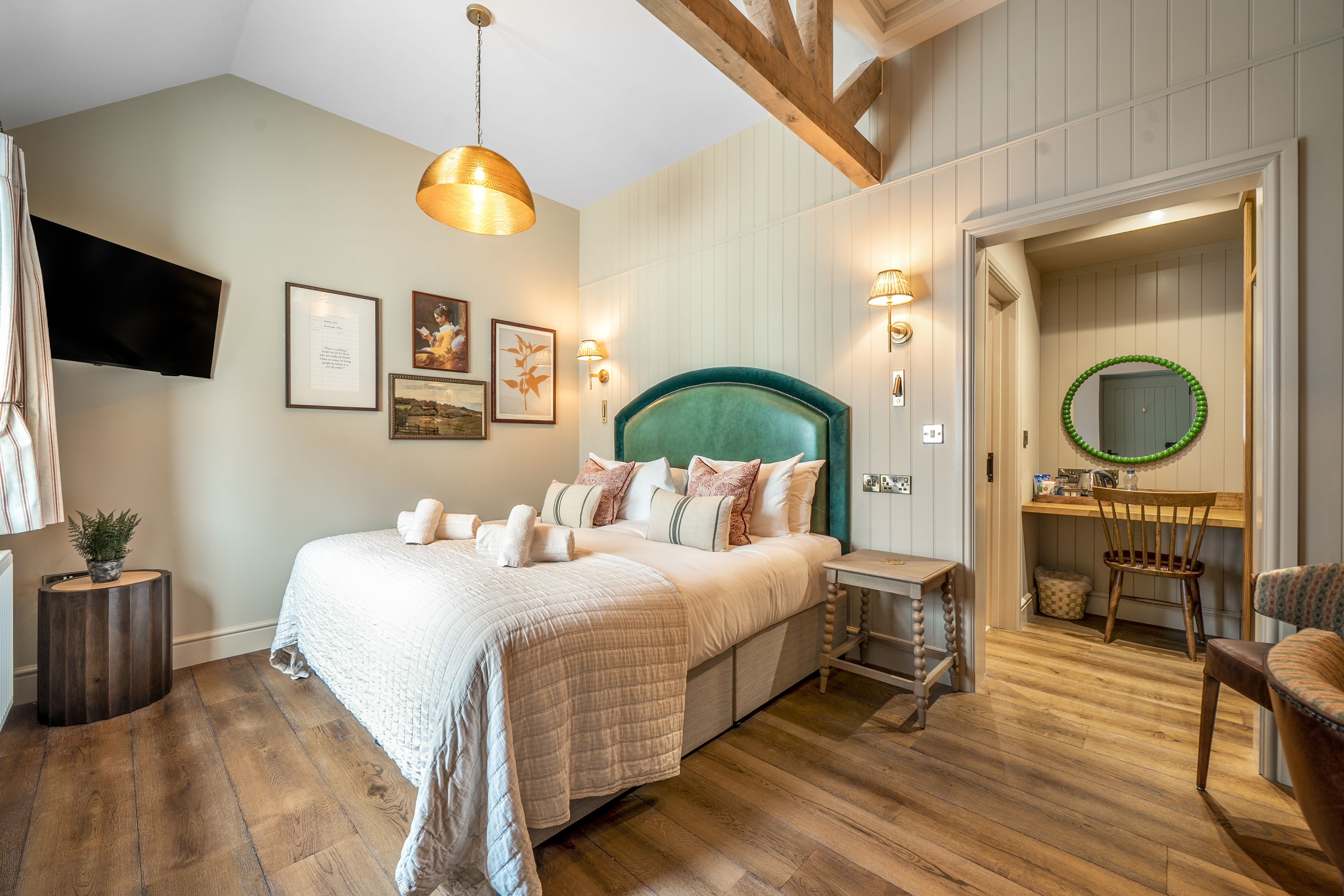 A bedroom with a bed, bedside tables, a TV, and a mirror.