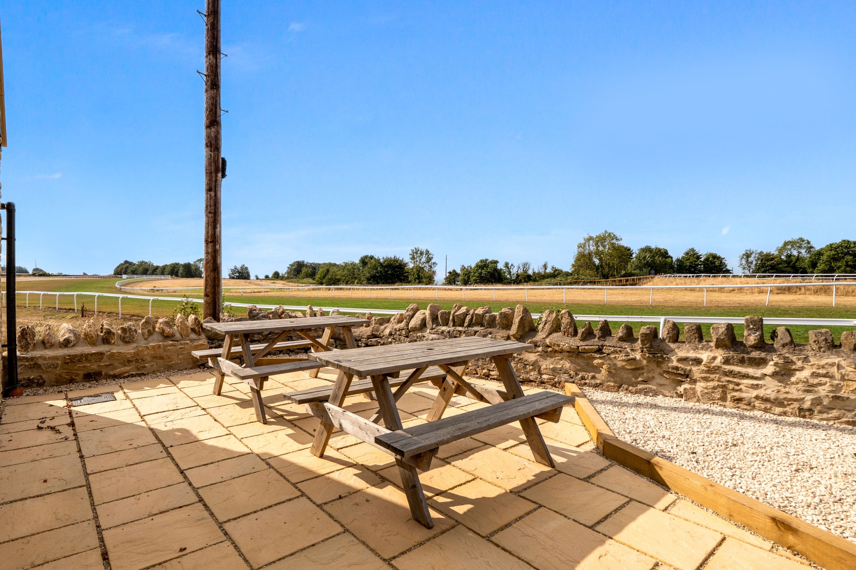 An outdoor seating area with picnic tables and a view of a sports field.