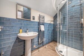 Une salle de bain avec une douche à parois de verre, un lavabo et un porte-serviettes.