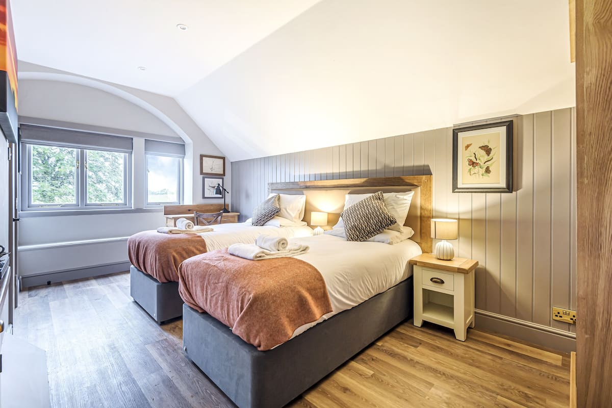 Un dormitorio moderno con una cama grande, dos mesitas de noche y vistas al exterior a través de un ventanal.