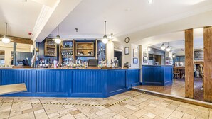 A bar area with a blue counter, tiled floor, and various bottles and glasses. - Charlcombe Inn (Bath)