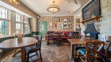 Een restaurant interieur met houten meubels, een visgraatvloer en een krijtbordmenu.