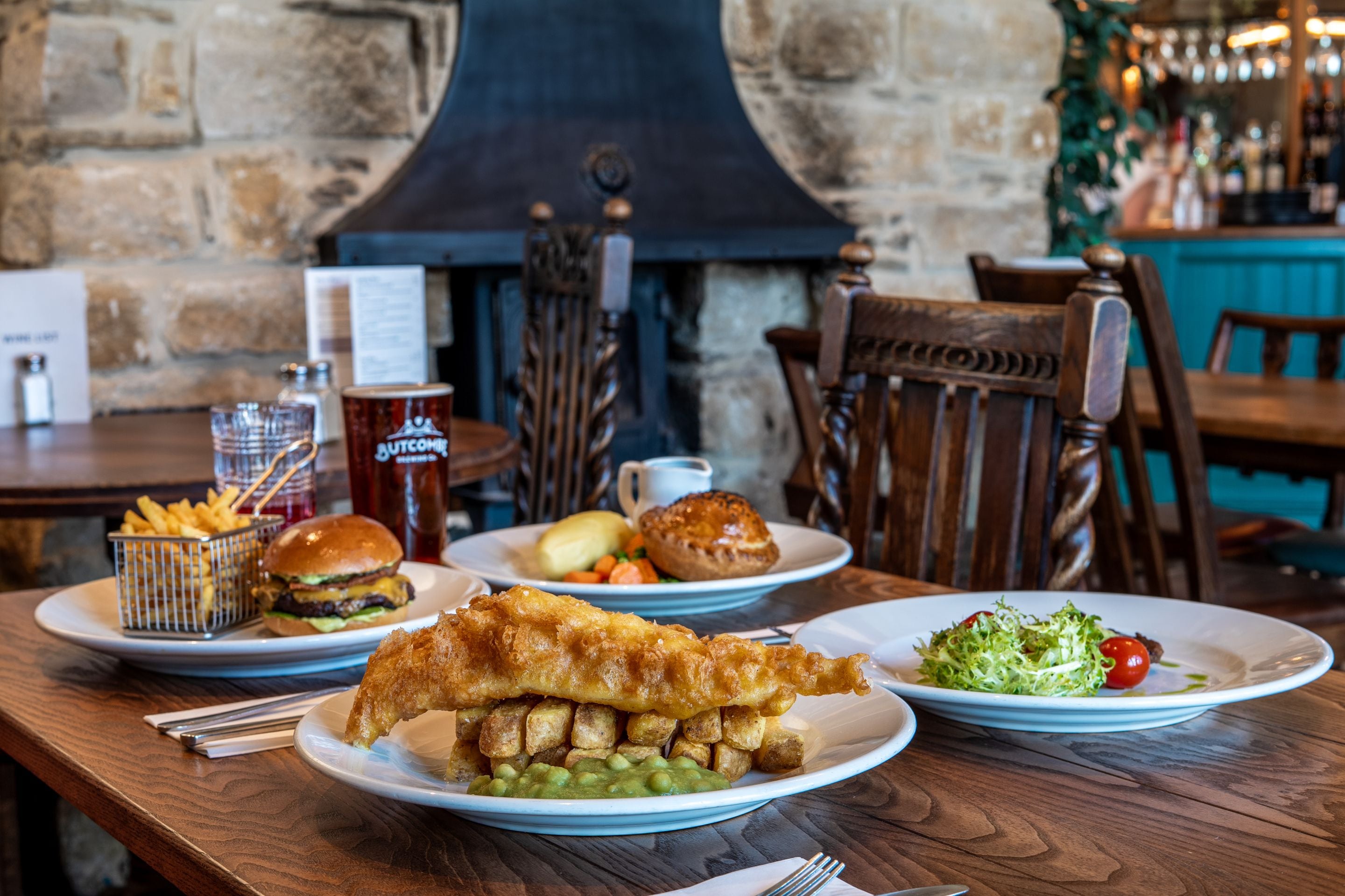 A table with a variety of dishes including fish and chips, a burger, and a salad.
