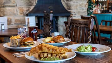 A table with a variety of dishes including fish and chips, a burger, and a salad.