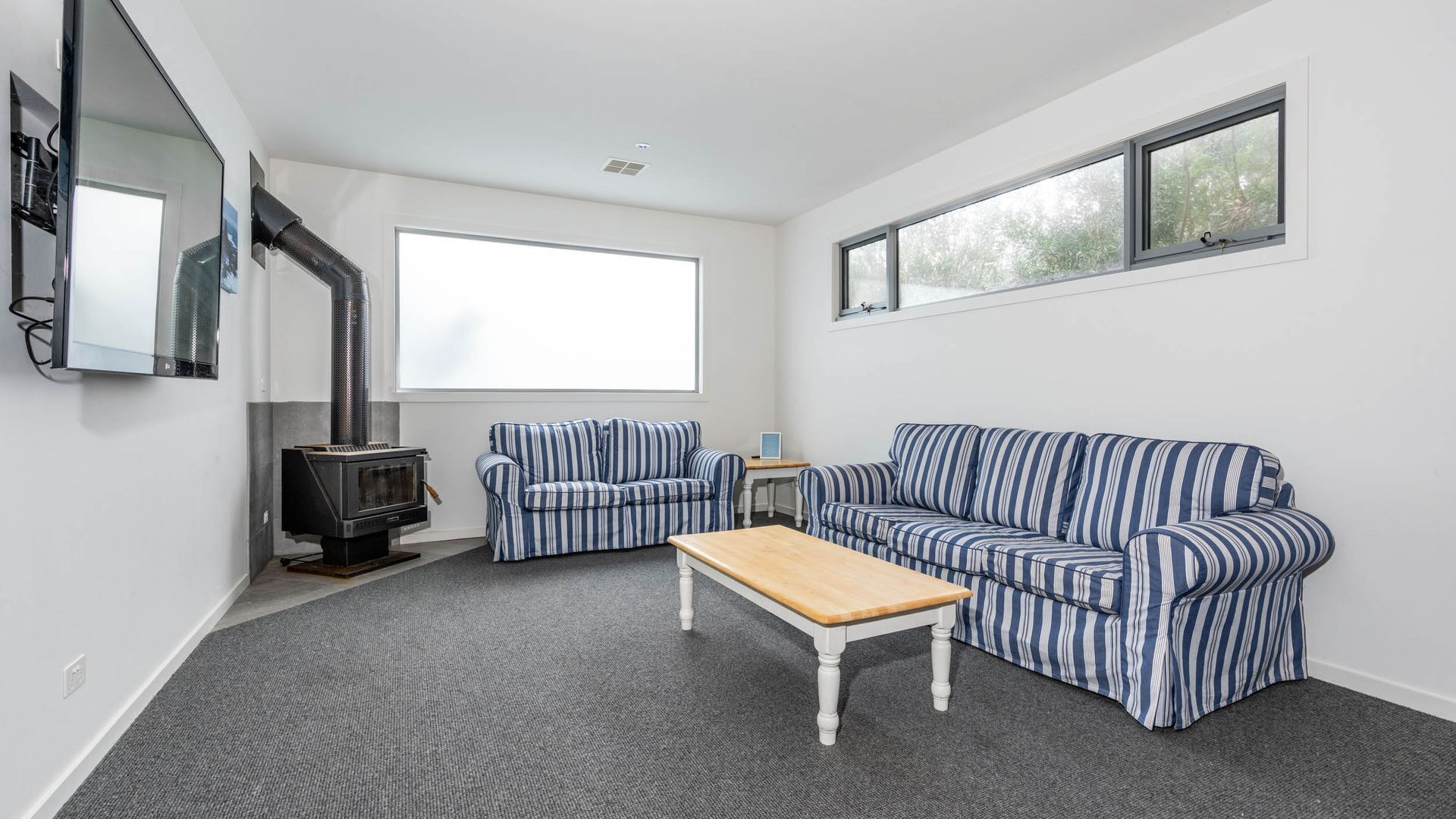 A living room with a sofa, a smaller sofa, a coffee table, a fireplace, and a large window.