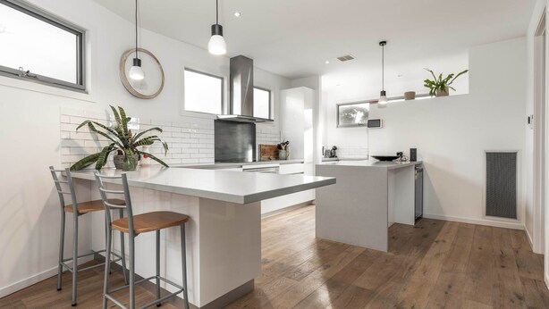 Una cocina moderna con una isla central, taburetes de bar, estufa y microondas.