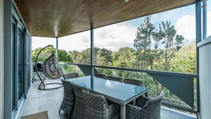 Un espacio de estar al aire libre cubierto, con mesa y sillas, con vistas a un paisaje natural.