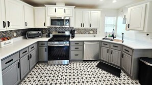 A modern kitchen with white cabinets, a microwave, stove, and a dishwasher. - Spectacular panoramic views on nearly 10 acres, Stargazing, Spa, Family Friendly (Twentynine Palms)