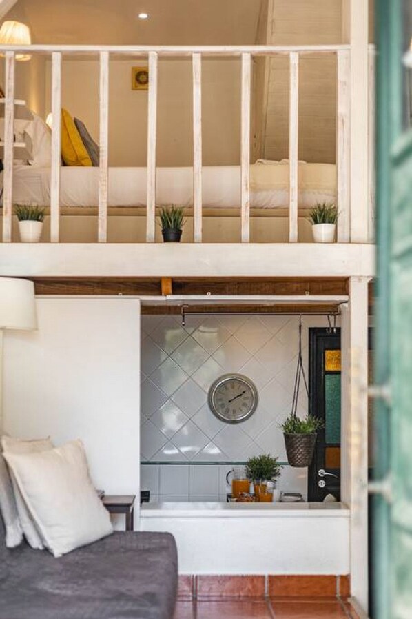 A loft-style bedroom with a bunk bed, a small kitchenette, and a dining area.
