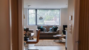 A modern living room with a sofa, coffee table, and a dining area. - Apartment Seven (Shrewsbury)
