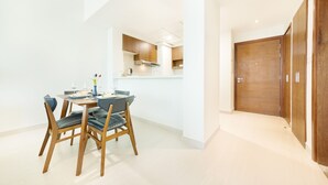 A modern kitchen with wooden cabinets, a dining table with chairs, and a view into the adjacent living area. - Maison Privee - Superb 1BR apartment overlooking Zabeel Park and Dubai Frame (Dubai)