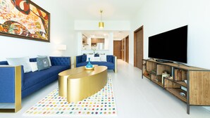 A modern living room with a blue sofa, a gold coffee table, and a flat-screen TV on a wooden stand. - Maison Privee - Superb 1BR apartment overlooking Zabeel Park and Dubai Frame (Dubai)