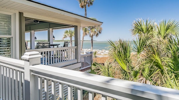 Una propiedad frente a la playa con un patio cubierto, mobiliario exterior y vistas al océano.