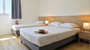 Une chambre d’hôtel avec deux lits, une tête de lit en bois, des lampes de chevet et un chapeau de paille posé sur l’un des lits.