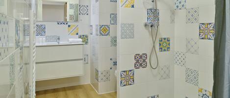 A bathroom with a shower, a sink, and a mirror.