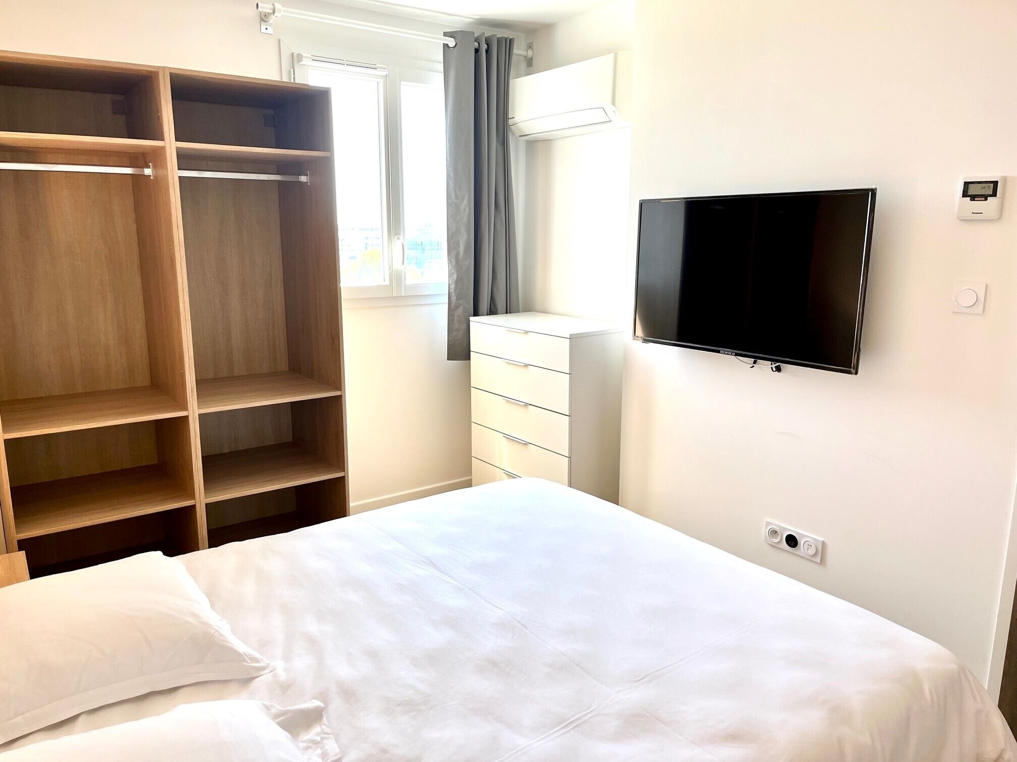 Une chambre à coucher comprenant un lit, une télévision, une armoire et une commode.