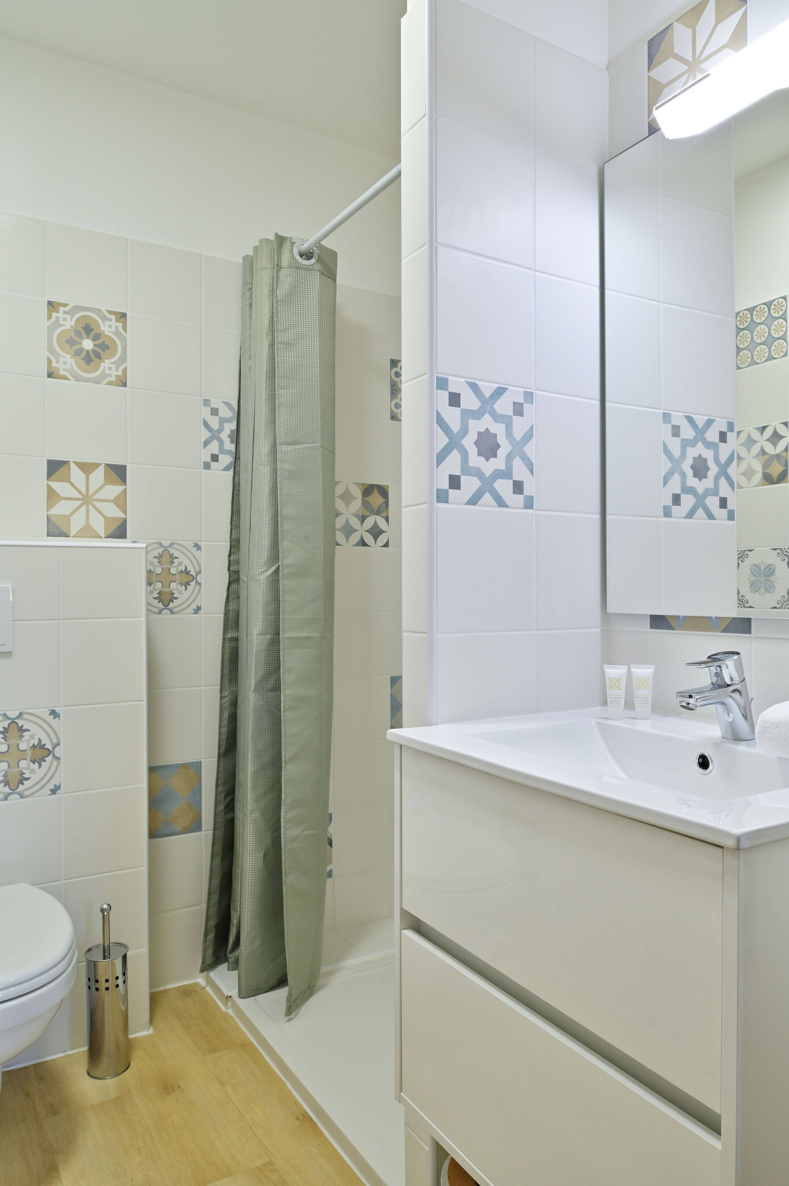 Une salle de bain avec un lavabo blanc, un miroir et un rideau de douche.