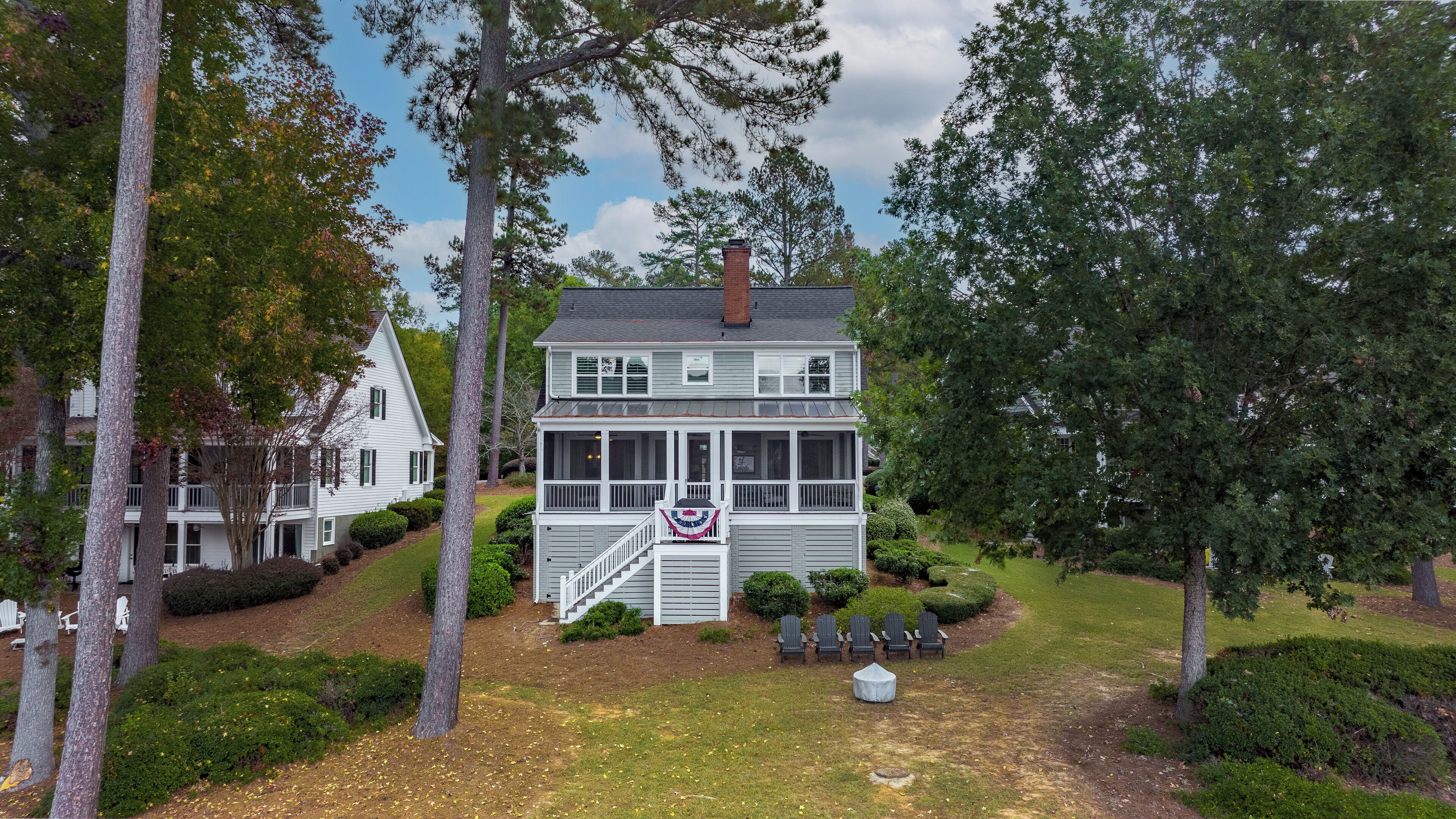 A two-story house with a porch, surrounded by trees and a well-maintained lawn.