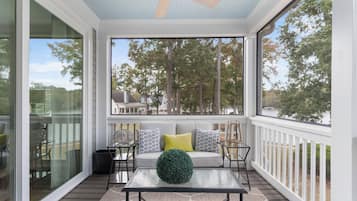 Relax in this serene outdoor space with a sofa, chairs, and a glass-topped table.