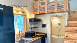 Una cocina compacta con refrigerador, estufa, lavamanos y armarios de madera.