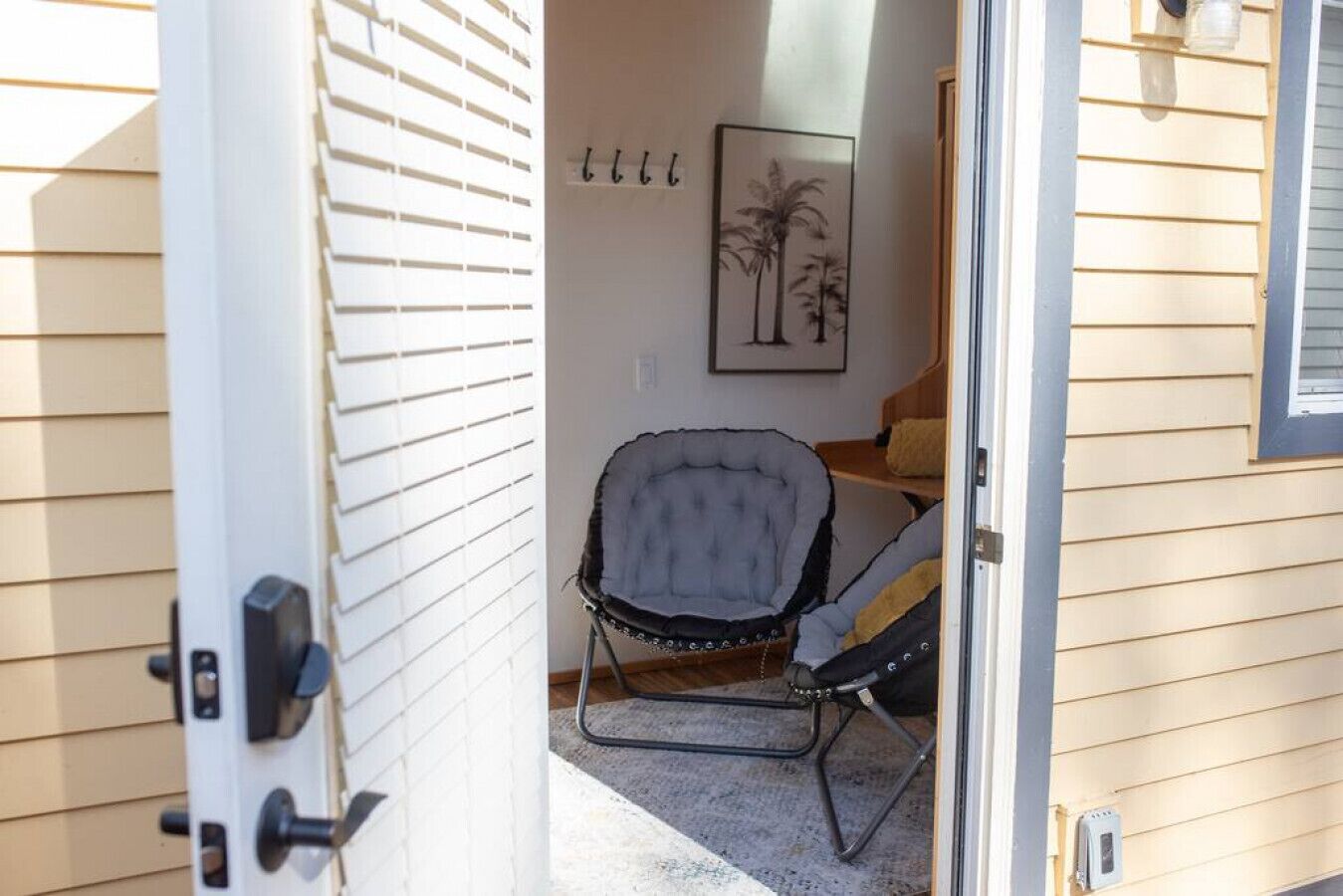 Una puerta que da a una habitación con una silla y un cuadro en la pared.