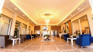 A spacious lobby with a high ceiling, recessed lighting, and a central floral arrangement. - Continent Hotel Kapadokus Thermal (Guzelyurt)