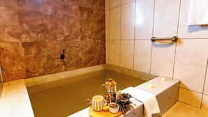 A bathroom with a bathtub, a towel rack, and a tray with a cup, a teapot, and a candle. - Continent Hotel Kapadokus Thermal (Guzelyurt)