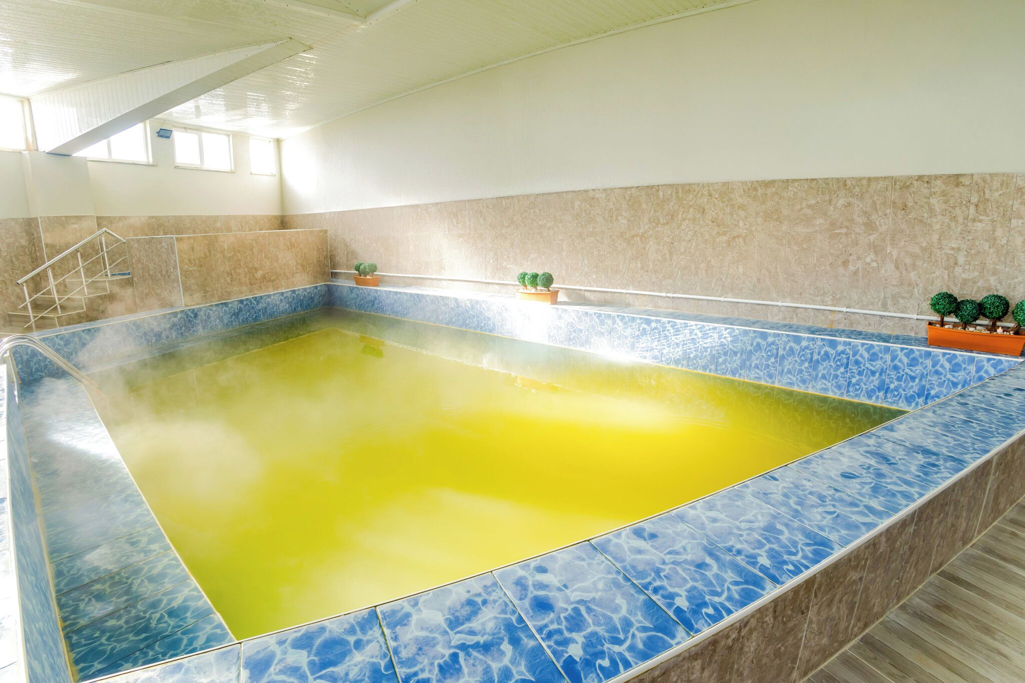 A large indoor swimming pool with a yellow center and blue tiles around.