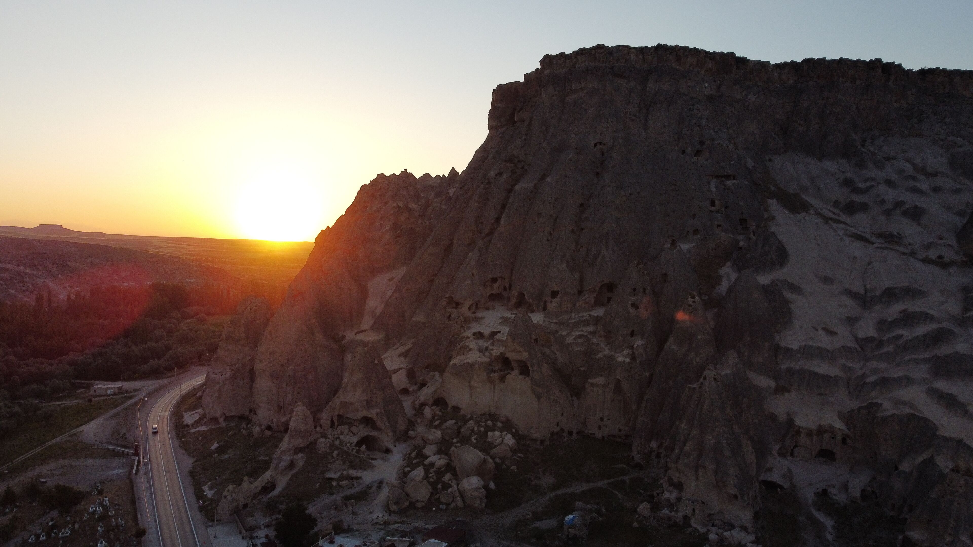 A mountainous landscape with a road leading towards a cliff.