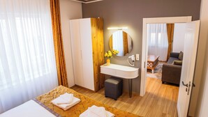A hotel room with a bed, a bathroom with a mirror, a sink, and a small table with a vase of flowers. - Continent Hotel Kapadokus Thermal (Guzelyurt)