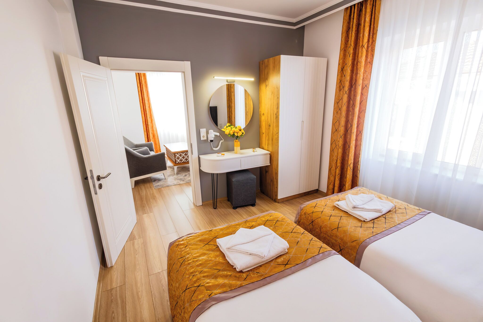 A hotel room with two beds, a bathroom, and a view of the outside.