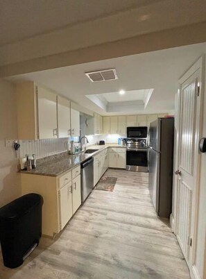 Cozinha moderna com armários brancos, eletrodomésticos de aço inoxidável e uma ilha central.
