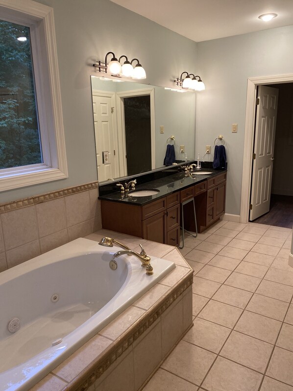 A bathroom with a large bathtub, double sinks, and a vanity with a mirror.
