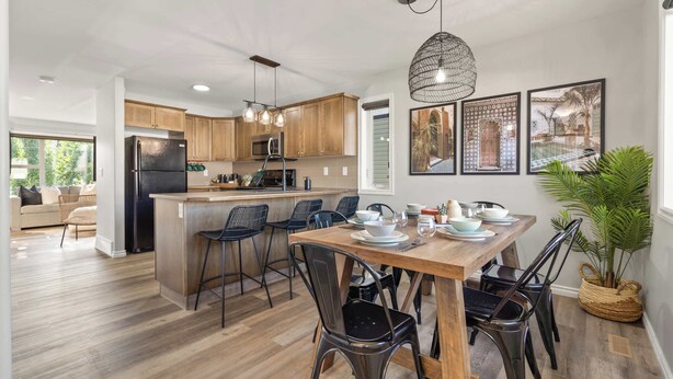 Una cocina moderna con armarios de madera, una isla central y un comedor con mesa y sillas de madera.