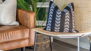 Una habitación con un sofá de cuero marrón, una silla de mimbre, una cesta tejida y una pared verde.