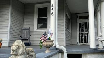 Une maison avec un porche, le numéro 456, une statue de lion et deux drapeaux américains.
