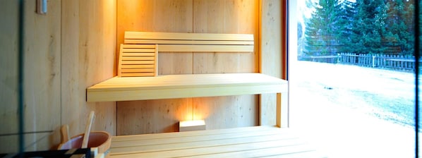 A wooden sauna with a bench and a small window.