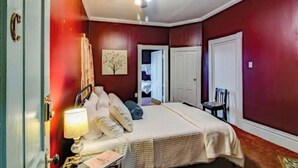 Ein Schlafzimmer mit Bett, Nachttisch, Lampe, Deckenventilator und einer Tür.