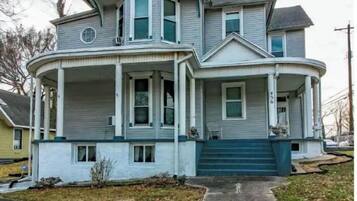 A two-story house with a wrap-around porch and a blue front door.