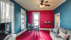 A room with a red carpet, a ceiling fan, a dining table with chairs, a grey sofa, and a window with blinds. - ❤DT Victorian Apt D❤ 1br~Walk to DT/APSU~Firepit❤ (Clarksville)