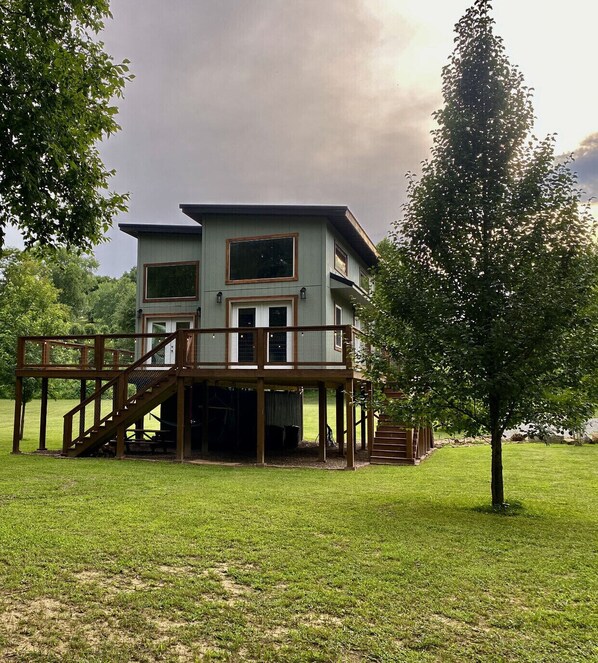A two-story house with a wooden deck and a staircase leading to the upper floor.