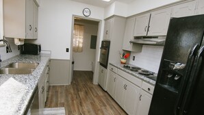 A kitchen with white cabinets, a stainless steel sink, a stove, and a black refrigerator. - The Ranch Near Boomer Lake (Stillwater)