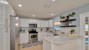 Una cocina moderna con armarios blancos, electrodomésticos de acero inoxidable y una isla central.