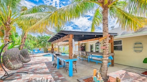 Un espacio al aire libre techado con piscina, bar y zona de estar.