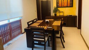 Een eetruimte met een lange houten tafel, zwarte stoelen en een kroonluchter.