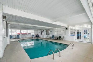 An indoor swimming pool with a clear view of the pool area, including the poolside chairs and the pool's edge. - Whale's Tale - Boutique Studio Condo w/Pool 🐳 (Hampton)