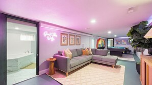 Una sala moderna con un sofá modular, una mesa de billar y un letrero de neón.