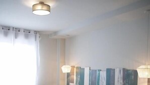 A hotel room with two beds, a large window with curtains, and a wall-mounted artwork. - Hotel Rural Covarrubias (Covarrubias)