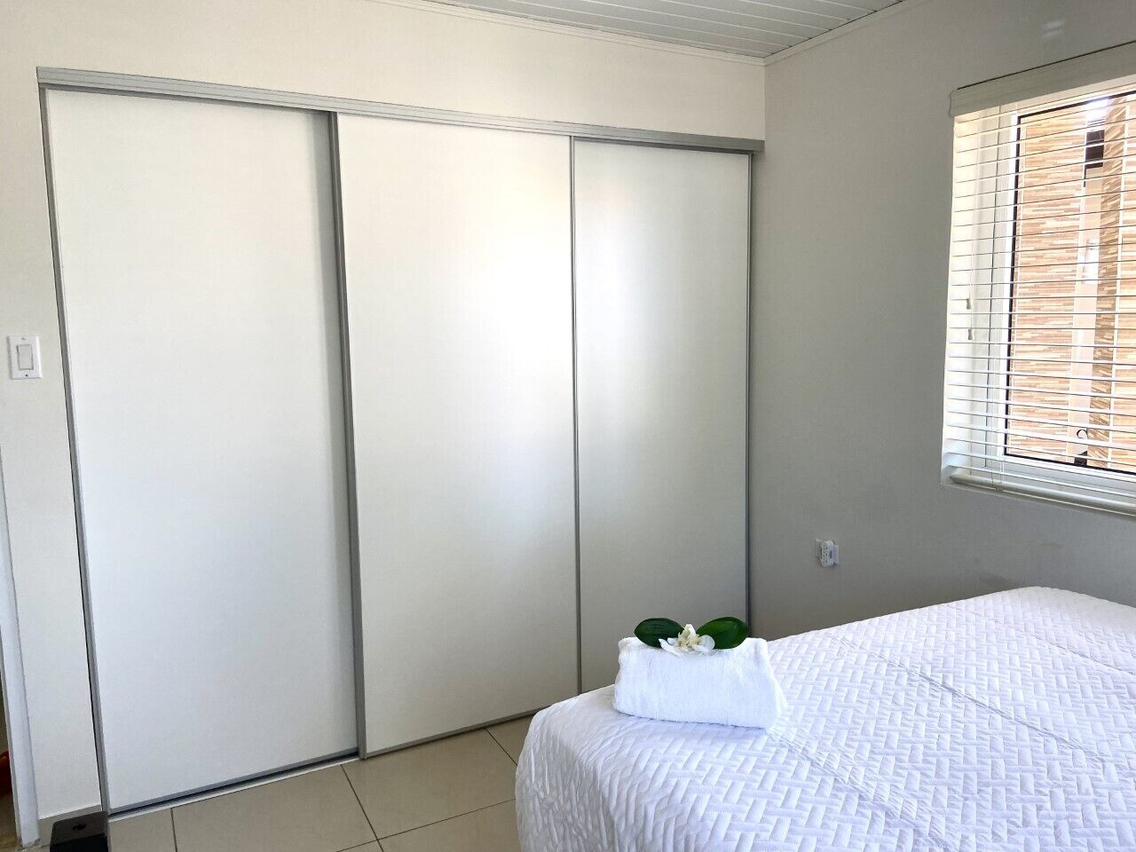Une chambre à coucher avec un lit, une fenêtre avec des stores et une porte coulissante.