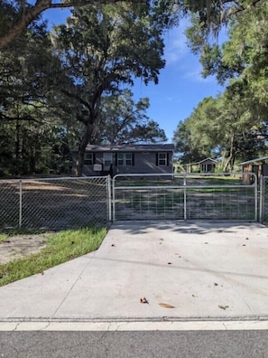 A gated residential area with a house, a fenced yard, and a clear sky.